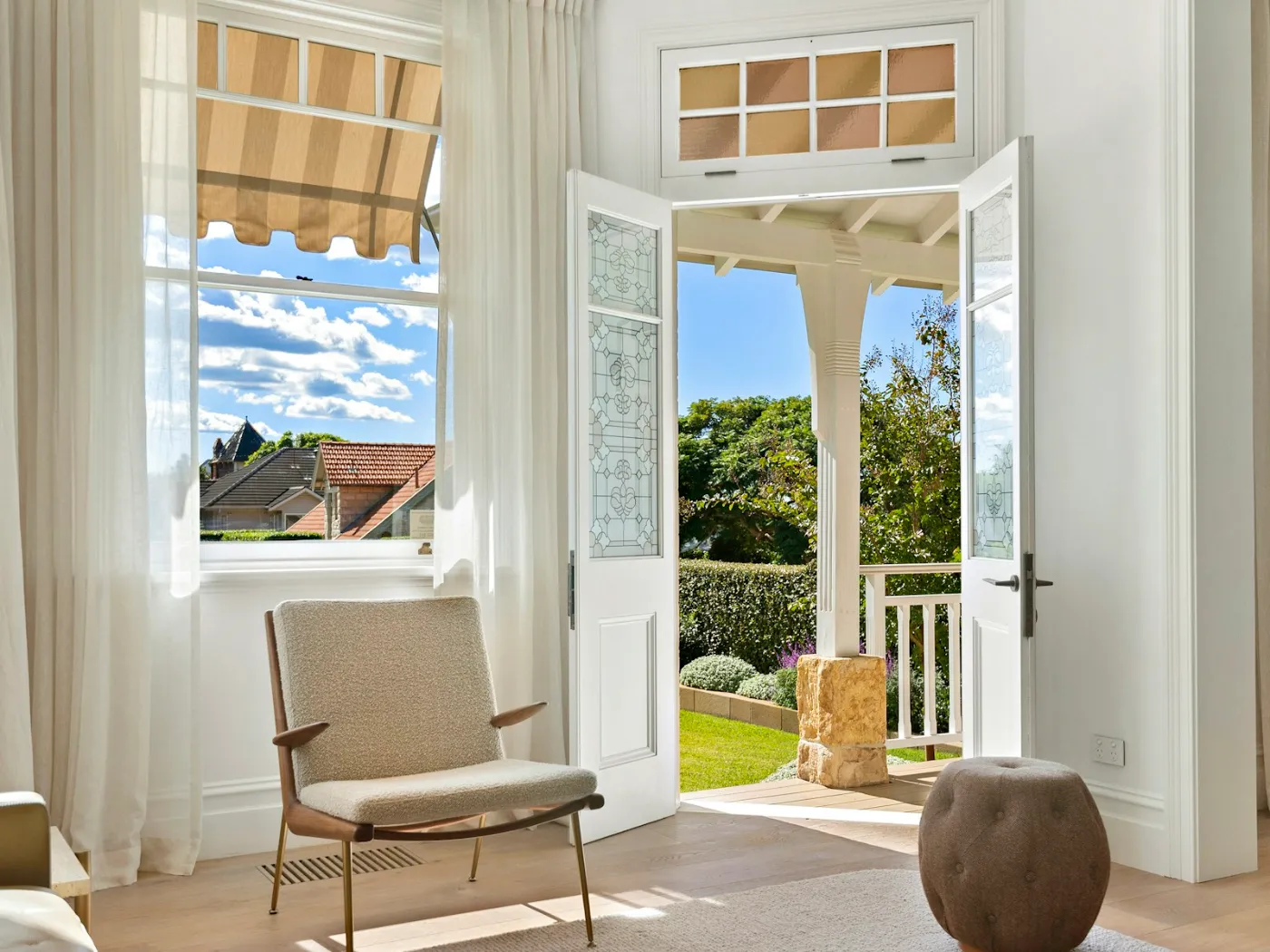 Porte-fenêtre blanche à deux vantaux ouverte sur un jardin, vue de l'intérieur